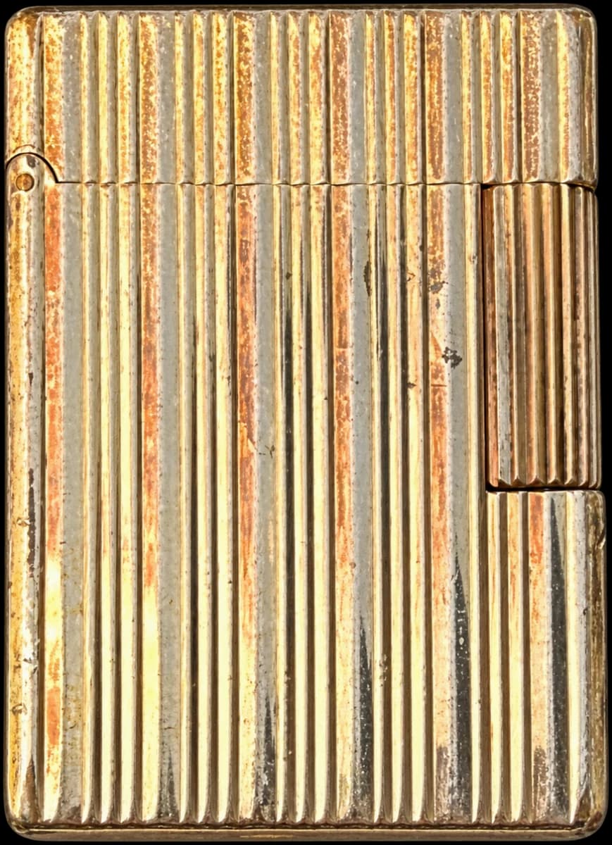 Briquet rectangulaire fermé de couleur dorée, décor de cannelures verticales et patine visible